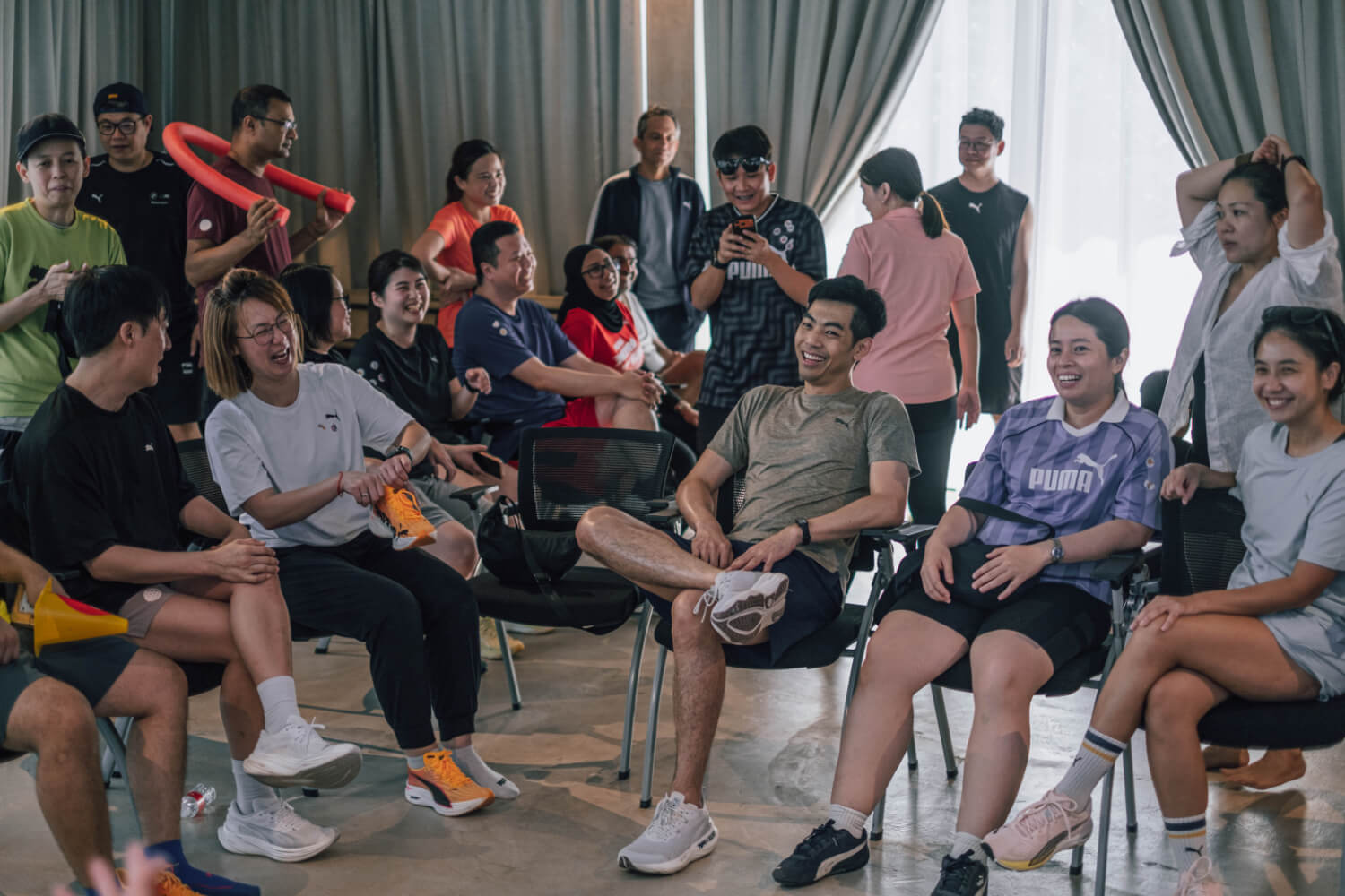 Puma group leaders seated in a circle laughing and sharing feedback during an indoor corporate retreat workshop