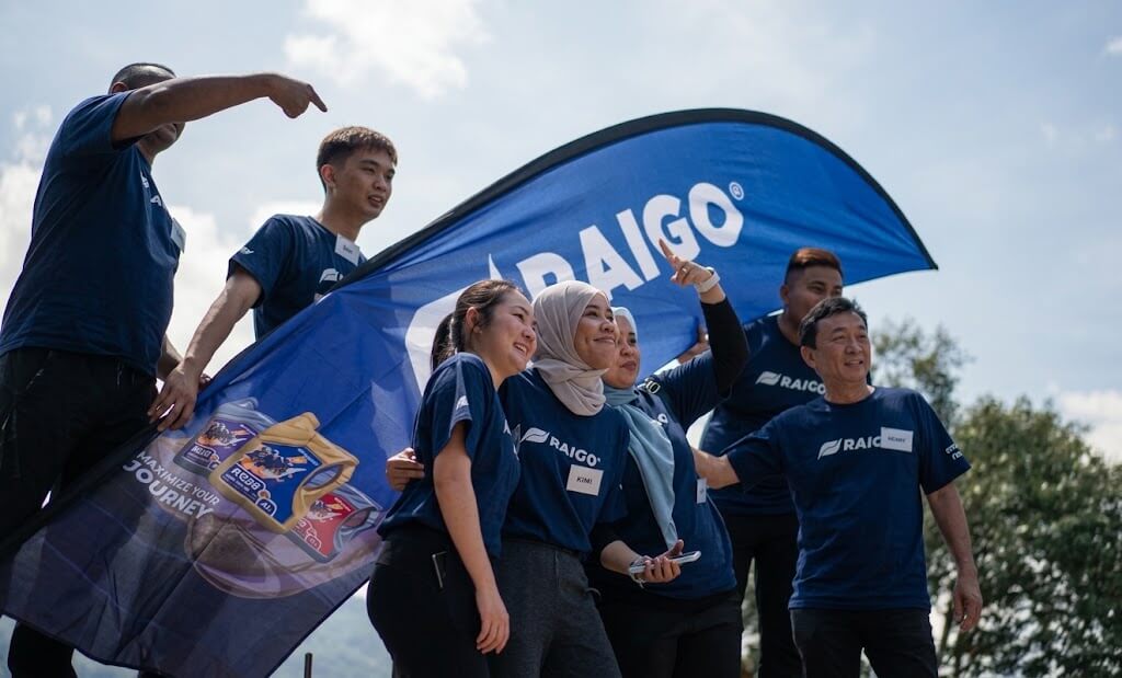 Raigo team members posing together with a branded flag during an outdoor treasure hunt team building activity