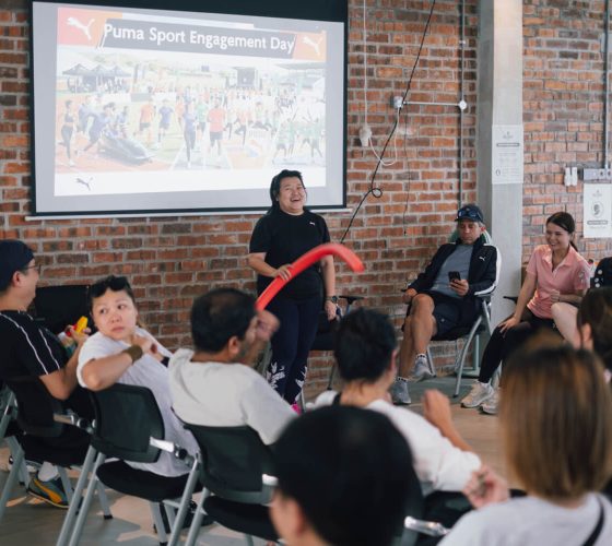 Team building trainer explaining game rules to Puma employees in a meeting hall during a corporate engagement day